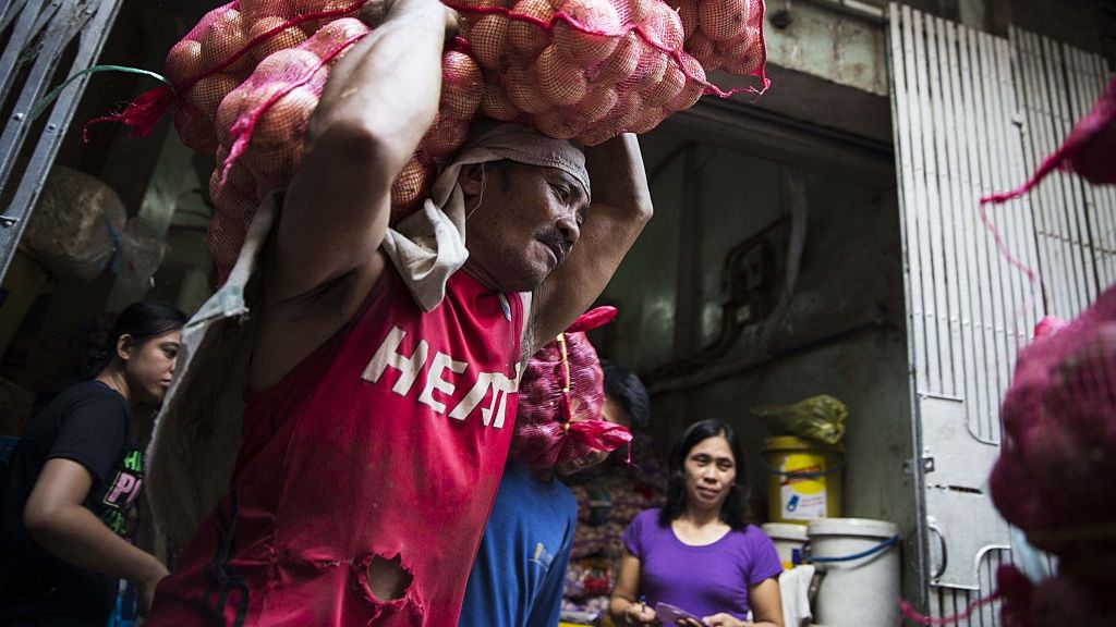 Pracownik niesie torby z cebulą na targu Divisoria w Manili na Filipinach 