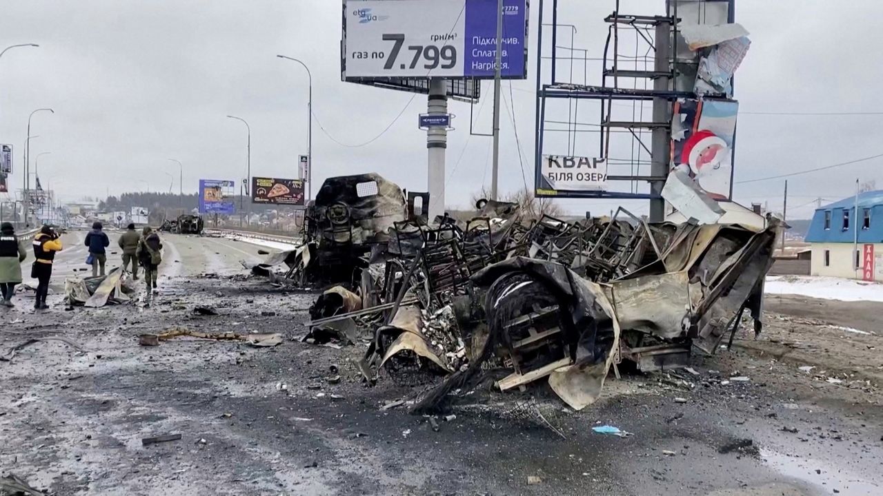 Ludzie przechodzący obok wraków samochodów na ulicy w miejscowości Bucza.