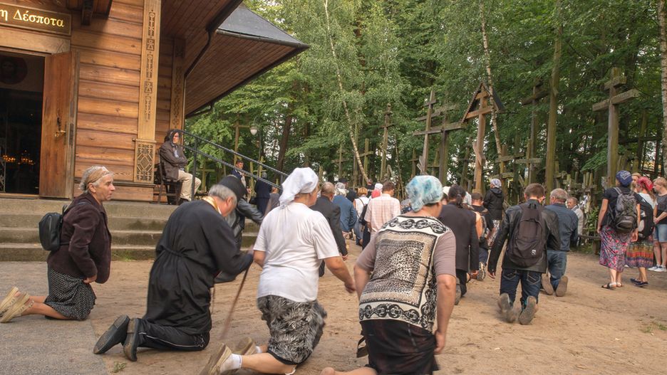 Pielgrzymi okrążają na klęczkach cerkiew, stojącą na Grabarce