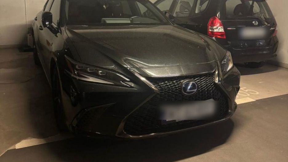 Czarny samochód marki Lexus zaparkowany w podziemnym garażu obok ciemnego pojazdu marki Honda.