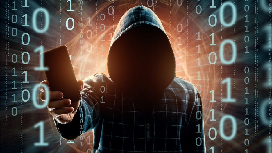 A young hacker in a hood hacks a smartphone, a hacker attack, a silhouette of a man, mixed media. The concept of a sudden attack, cryptography, data security, mobile Internet.
