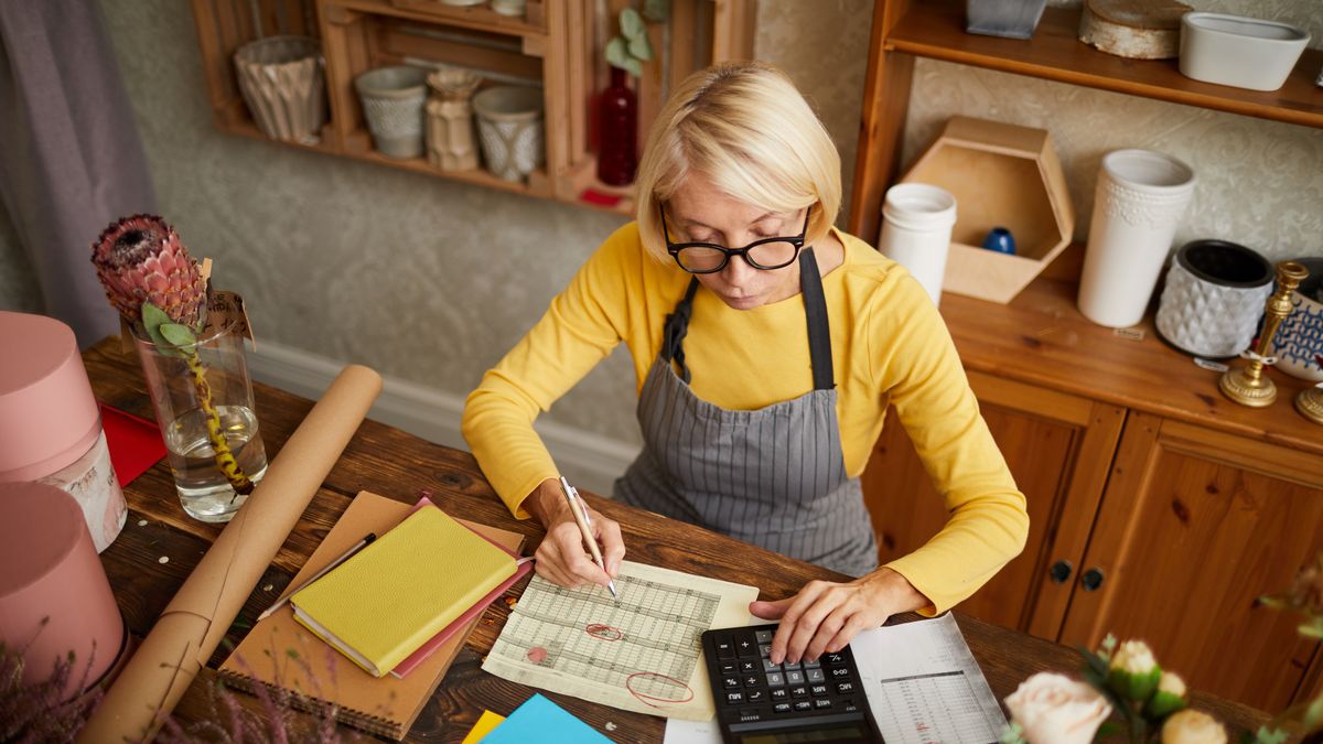 Mature Woman AccountingHigh angle portrait of female businesswoman counting finances using calculator in small shop, copy spacecounting, money, filling, form, calculator, manager, managing, finance, budget, accounting, bookkeeping, tax, taxes, mature, senior, small, business, owner, female, woman, businesswoman, work, occupation, shop, keeper, shopkeeper, flower, florist, financial, problem, payment