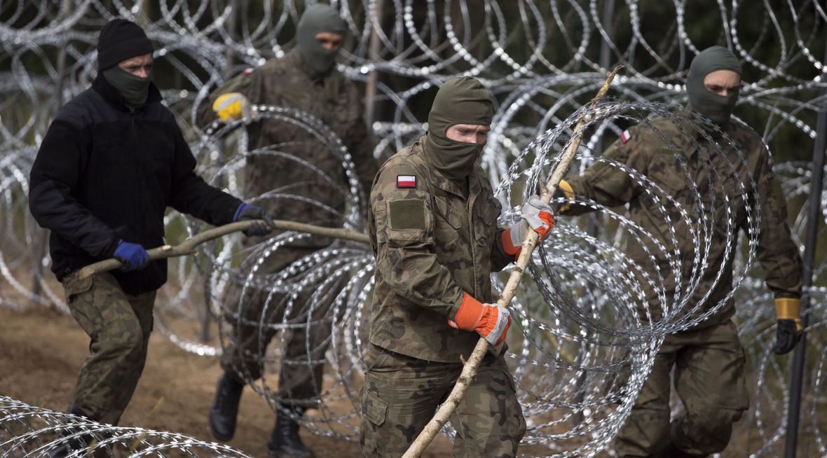 Polscy żołnierze rozciągają zasieki z drutu kolczastego. Strefa przygraniczna, okolice Krynek. wrzesień 2021 roku