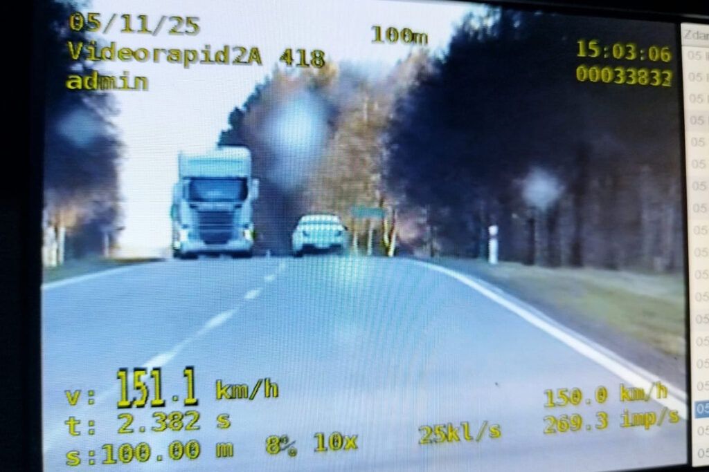 Ciężarówka poruszająca się z prędkością 151,1 km/h na drodze, obok białego samochodu osobowego.