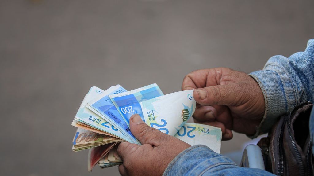 Palestinians Withdraw Cash From Bank of Palestine
A man counts Israeli shekel banknotes as Palestinian public sector employees withdraw cash from a Bank of Palestine Plc bank branch during the truce in Khan Yunis, Gaza, on Thursday, Nov. 30, 2023. The Palestinian Authority paid salary advances after delays caused by the Israel-Hamas war. Photographer: Ahmad Salem/Bloomberg via Getty Images
Bloomberg
civil unrest, religious conflict, armed conflict, banks, banking, finance, financial, industries, palestinian authority gaza, war, military actions, middle east and north africa, business news, unrest, emea