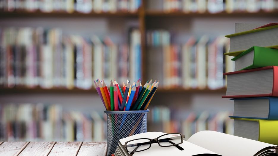 digital composite of school materials on table with library background