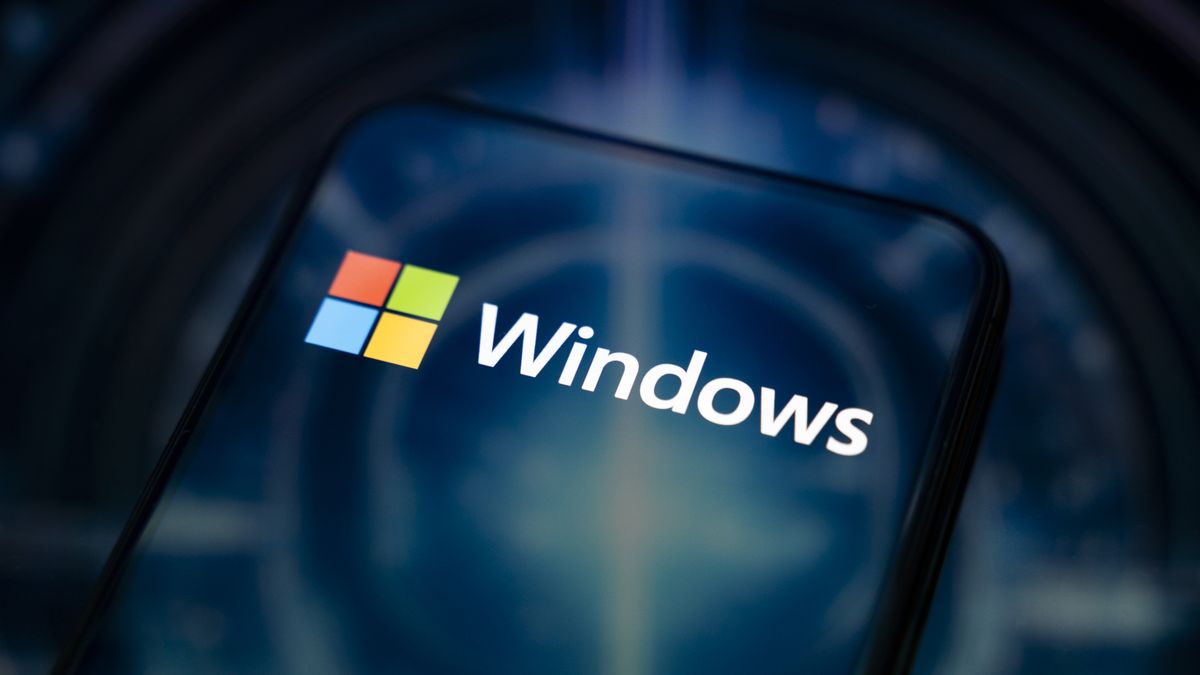 The Windows logo appears on the screen of a smartphone reflecting an abstract illustration in blue colors. Microsoft releases a major update to Windows 11 (25H2) and Windows 10 support ends permanently on October 14. In Creteil, France, on October 9, 2025. (Photo by Samuel Boivin/NurPhoto via Getty Images)