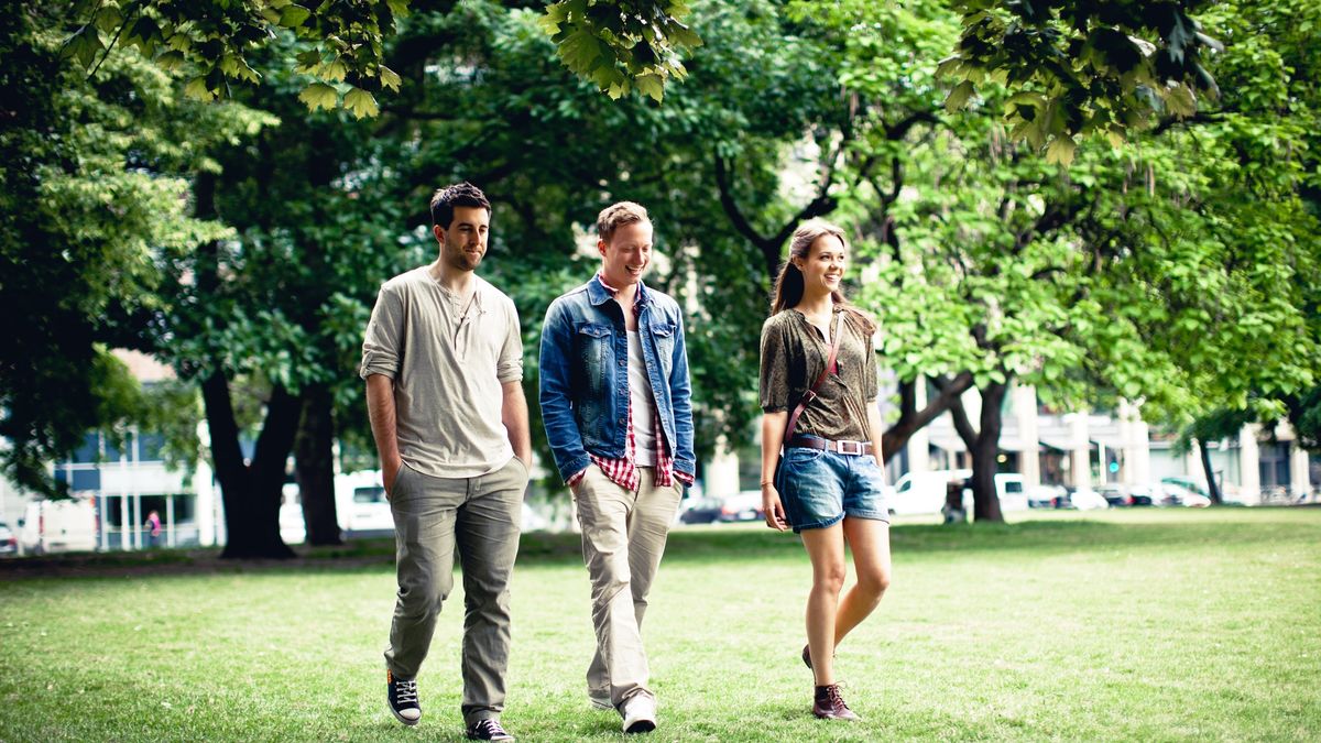 Trzy młode osoby idą przez park