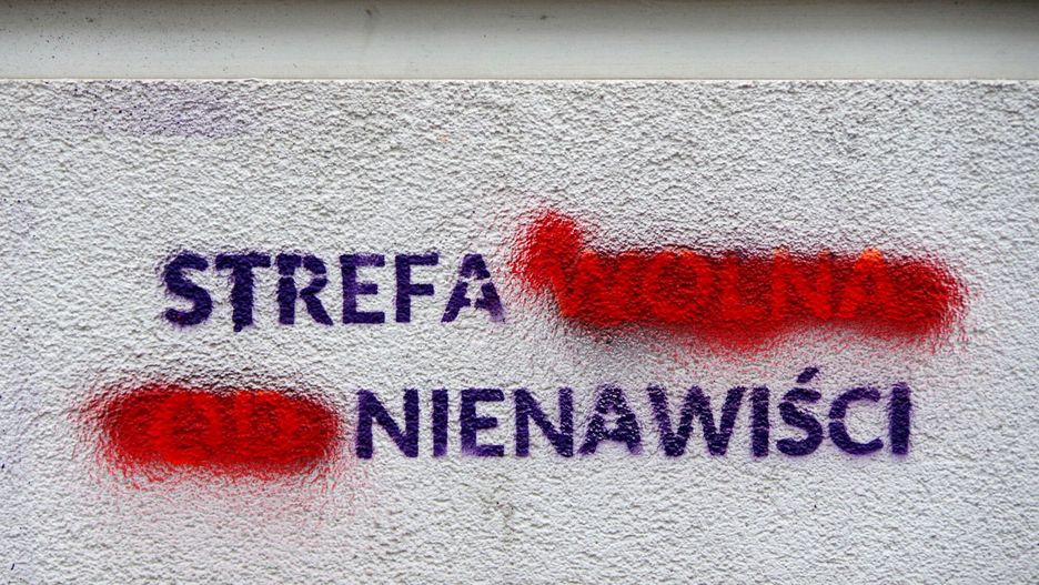 Napis na murze budynku częściowo zamalowany zmieniający znaczenie: Strefa (wolna od) nienawiści...