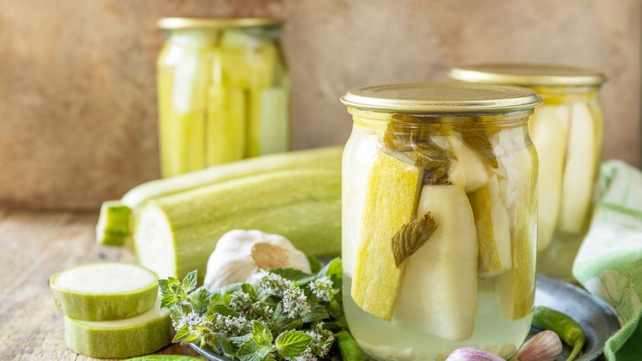 Healthy homemade fermented food. Pickled zucchini with mint preserved canned in glass jar. Home economics, autumn harvest preservation. Copy space.