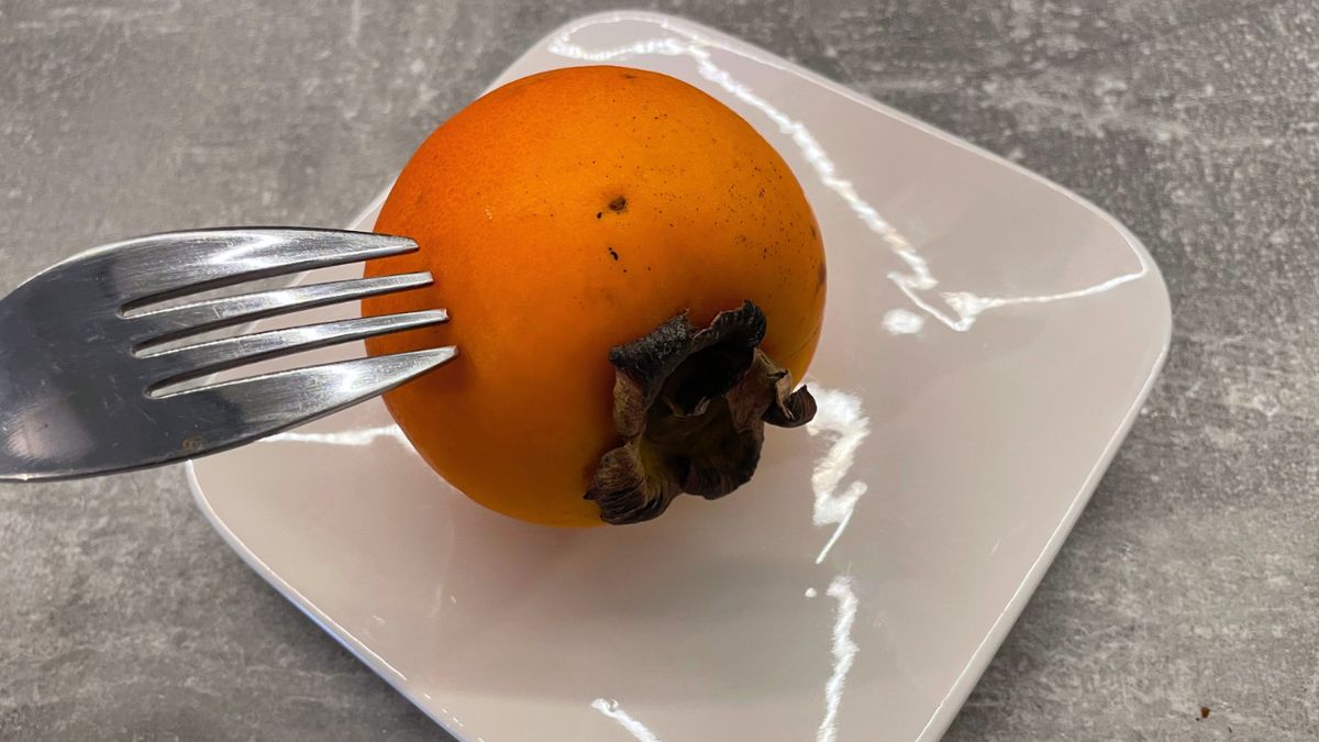 Owoc kaki na talerzyku i widelec