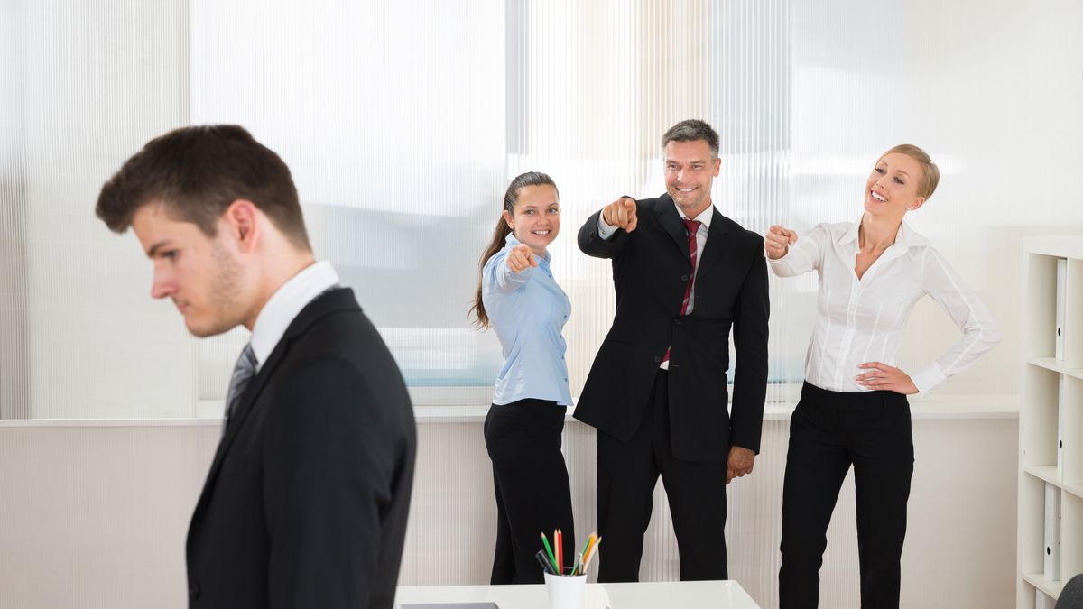 Happy Businesspeople Teasing Young Businessman Alone In Office