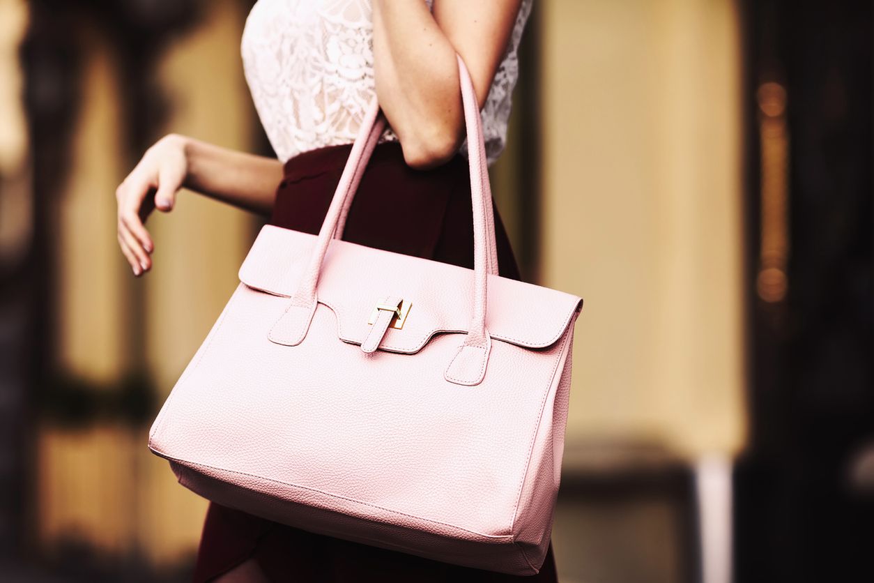 Elegant outfit. Closeup of leather bag in hands of stylish woman. Fashionable girl on the street. Female fashion. City lifestyle. Toned. 