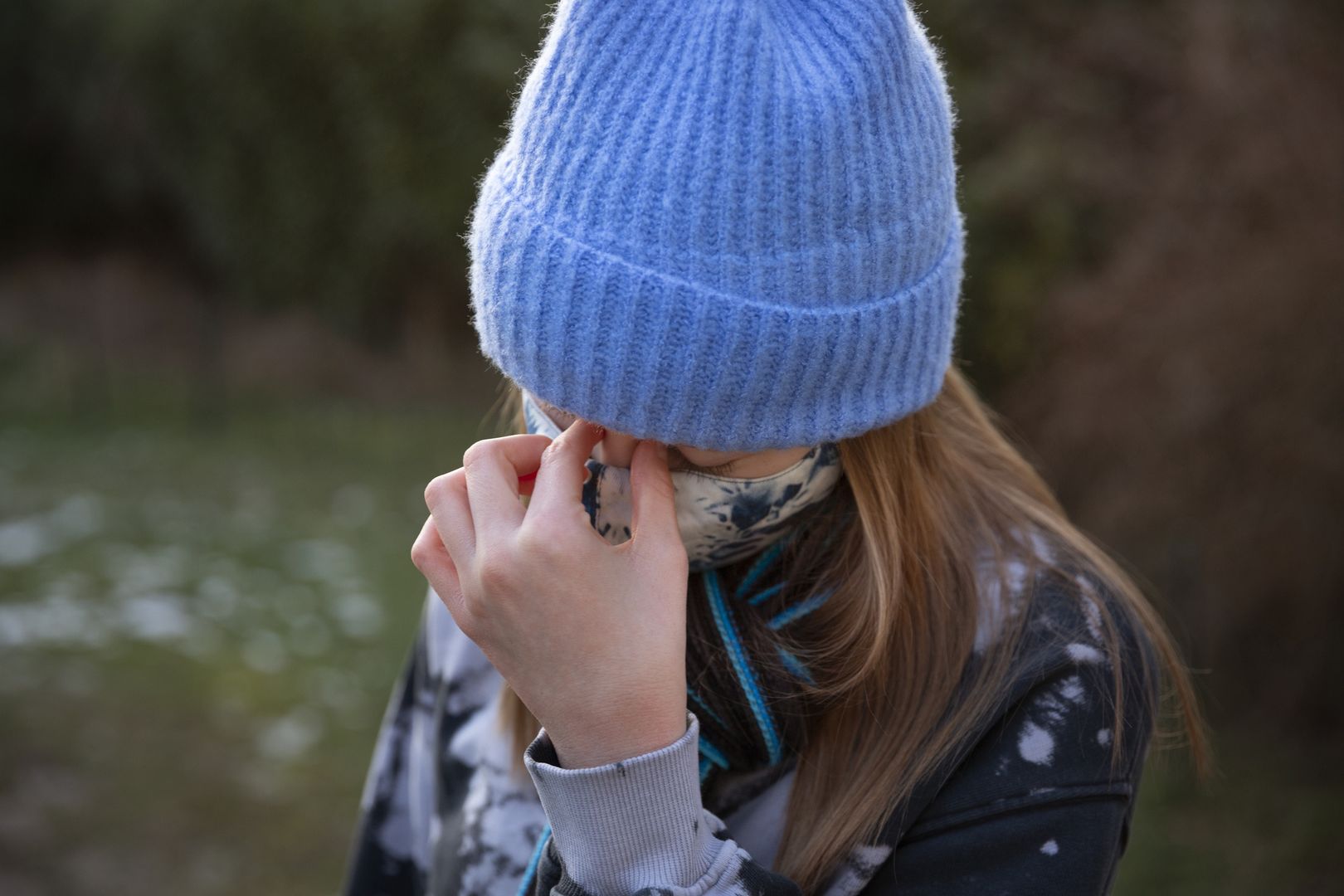 Teenage girl wearing protective face mask and rubbing bridge of nose in tensionElva Etienne