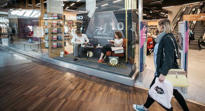 Czytający i słuchający muzyki ludzie w witrynach salonów Empik na 70-lecie sieci
