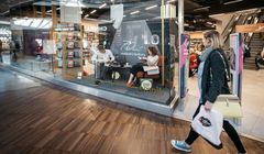 Czytający i słuchający muzyki ludzie w witrynach salonów Empik na 70-lecie sieci