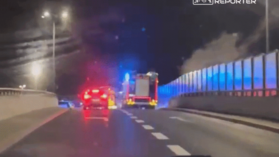 Na drodze w nocy zatrzymane samochody, w tym wóz strażacki z włączonymi sygnalizatorami świetlnymi.