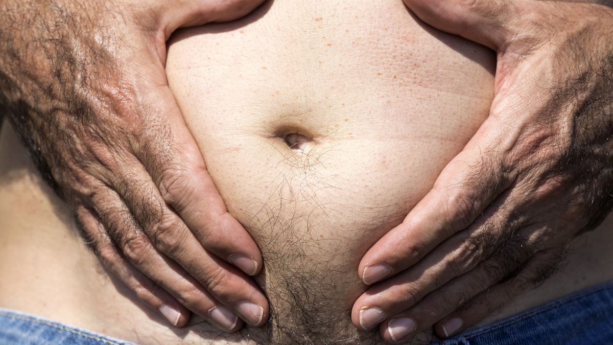 A close-up image of a men mature with  belly fat pinching itself, white-skinned, with jeans shorts in the light of the Sun in the beach
Belly of a man with some belly fat. Abdominal fat. Valencia, Spain.
Jose A. Bernat Bacete