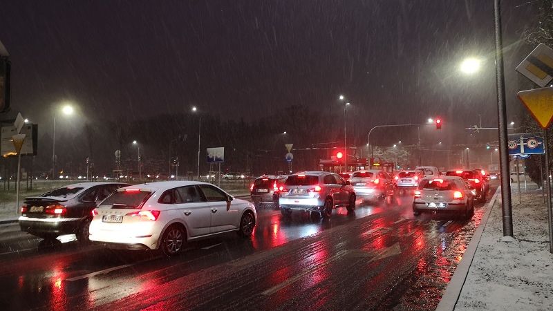 samochody oczekujące przed skrzyżowaniem na czerwonym świetle; opady deszczu i śniegu