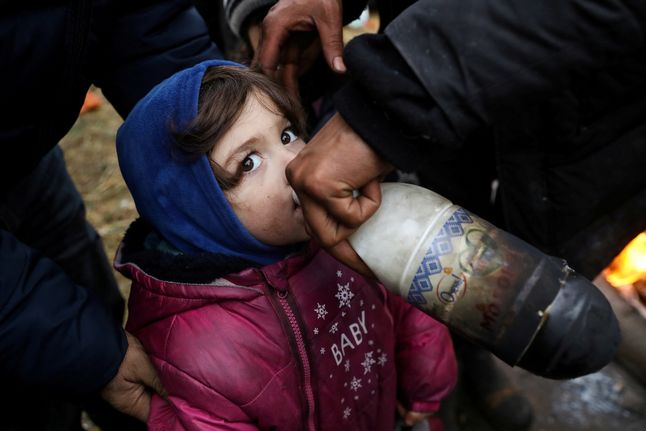 18.11.2021 r., Białoruś. Dziecko pije wodę, znajdując się w obozie migrantów przy granicy białorusko-polskiej w okolicach Kuźnicy.