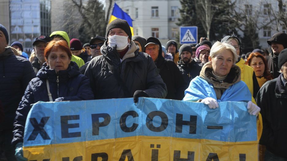 TemporaryPeople hold a Ukrainian flag with a sign that reads: "Kherson is Ukraine", during a rally against the Russian occupation in Kherson, Ukraine, Sunday, March 20, 2022. Ever since Russian forces took the southern Ukrainian city of Kherson in early March, residents sensed the occupiers had a special plan for their town. Now, amid a crescendo of warnings from Ukraine that Russia plans to stage a sham referendum to transform the territory into a pro-Moscow "people's republic," it appears locals guessed right. (AP Photo/Olexandr Chornyi)AP