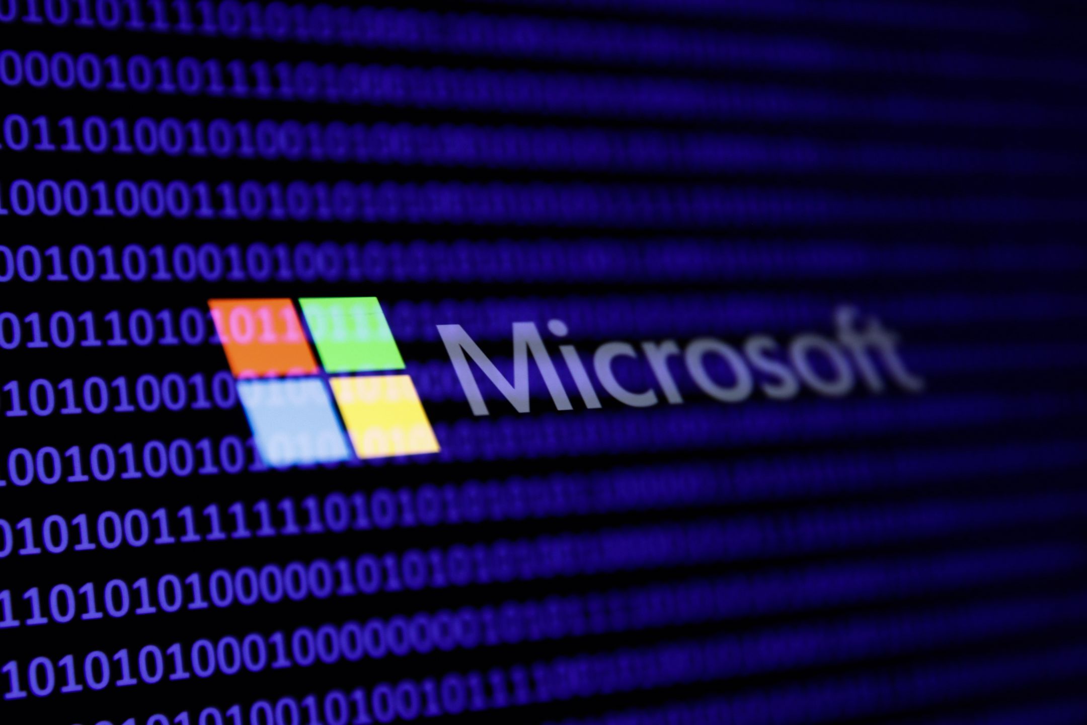 A binary code and Microsoft logo are seen in this multpiple exposure illustration photo taken in Krakow, Poland on February 21, 2024. (Photo by Jakub Porzycki/NurPhoto via Getty Images)