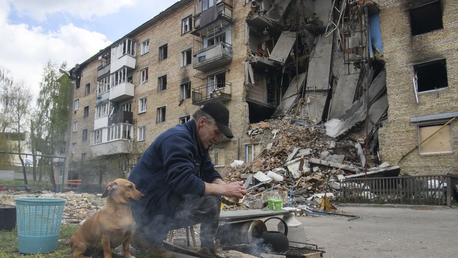 Local man warms water on the fire close to a residential building destroyed during Russia's invasion of Ukraine in Hostomel, Ukraine April 29, 2022. (Photo by Maxym Marusenko/NurPhoto via Getty Images)