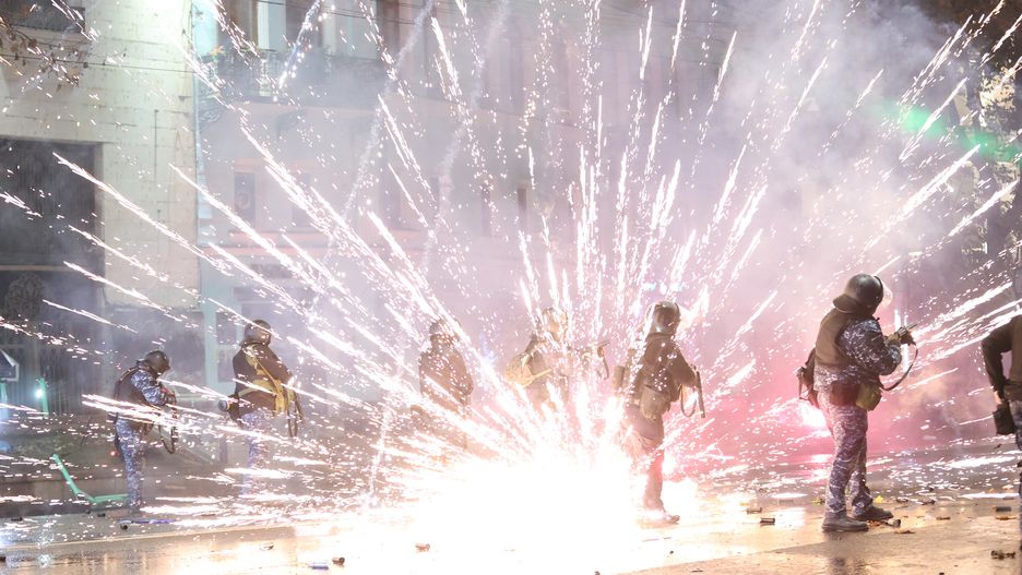 TBILISI, GEORGIA - DECEMBER 02: Protesters set garbage cans on fire and use pyrotechnics against the police while the police uses tear gas as they clash during a protest against the decision to suspend Georgia's EU accession negotiations until 2028 on December 2, 2024 in Tbilisi, Georgia. (Photo by Davit Kachkachishvili/Anadolu via Getty Images)