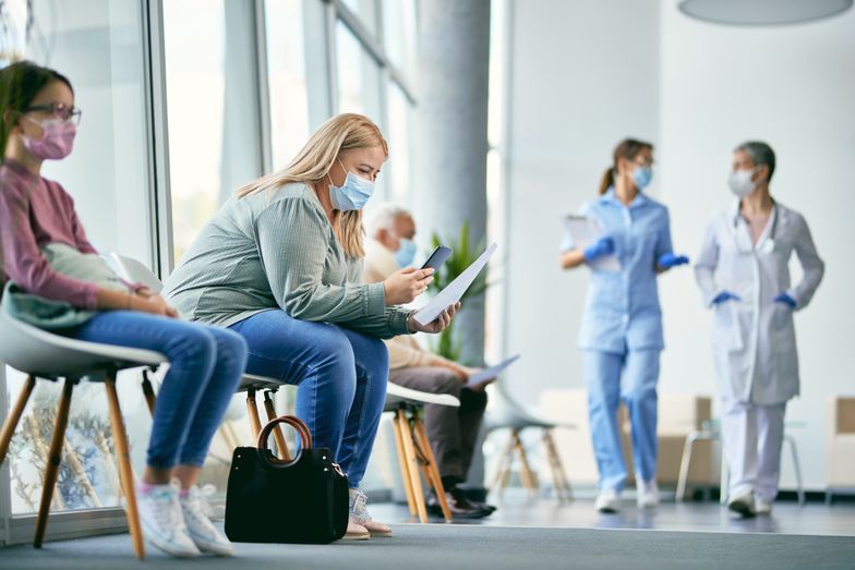 Woman with face mask using smart phone while reading her medical report in waiting room at the clinic.
Female patient examining medical paperwork and using mobile phone while sitting in hallway at the hospital.
Drazen Zigic