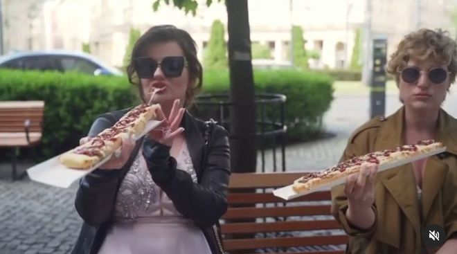 Zofia Zborowska i Aleksandra Domańska w sukniach balowych odtwarzają jedzenie zapiekanek