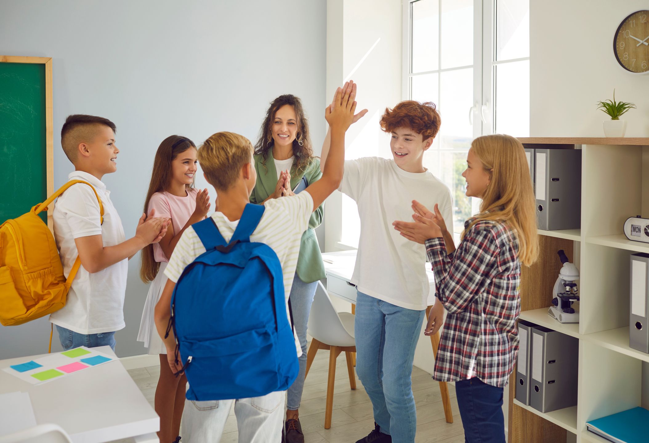  Alt: Klasa. Dzieci z nauczycielem stoją w kółku. Dwóch chłopców przybija sobie piątki. Reszta bije im brawo. 