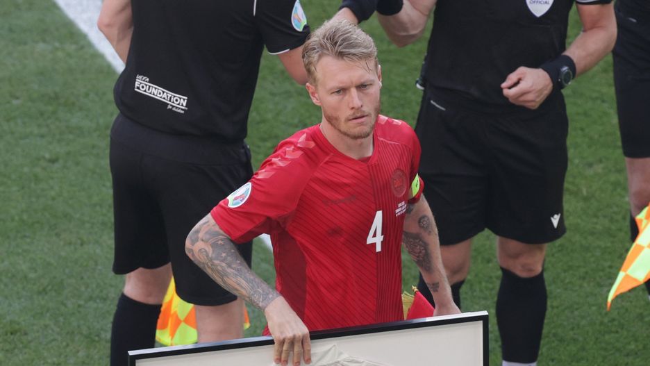 Kapitan drużyny Simon Kjaer trzyma ramkę koszulki poświęconej Christianowi Eriksenowi