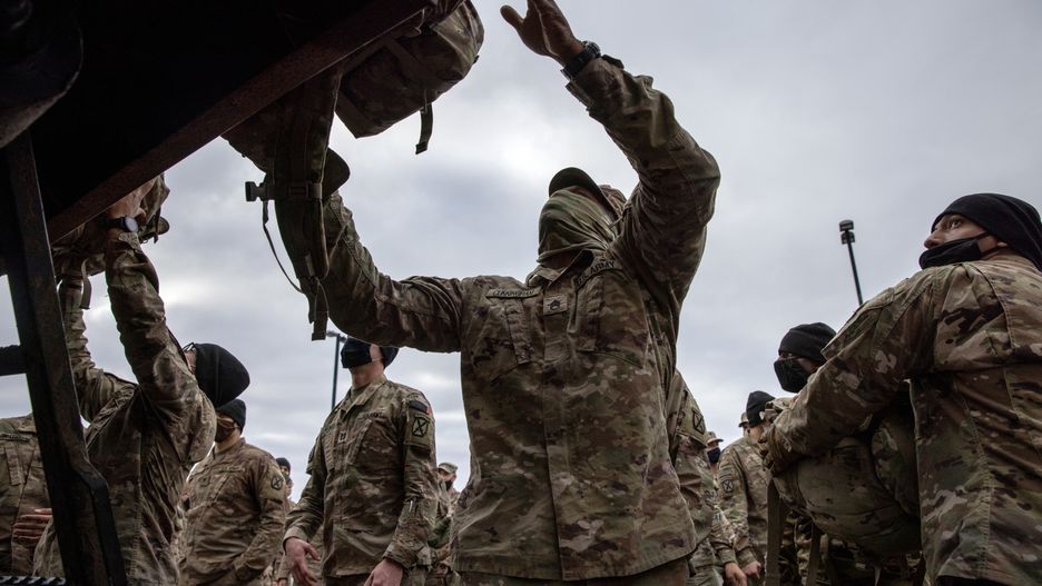 FORT DRUM, NEW YORK - DECEMBER 10: U.S. Army soldiers retrieve their duffel bags after they returned home from a 9-month deployment to Afghanistan on December 10, 2020 at Fort Drum, New York. The 10th Mountain Division soldiers who arrived this week are under orders to isolate with family at home or with fellow troops in barracks, finishing their quarantine just before Christmas. In the waning days of the Trump Administration and after 19 years of war, the U.S. military continues to reduce troop levels in Afghanistan.  (Photo by John Moore/Getty Images)