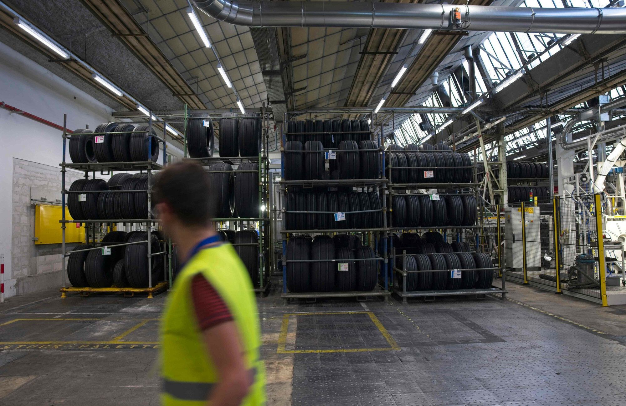 Fabryka opon Michelin we Francji - AFPThis photograph taken on October 27, 2022 shows a worker walking past stored tires in the Michelin plant in Saint-Doulchard, Central France. - The Michelin plant is the only factory in Europe to manufacture tires for aircraft. (Photo by GUILLAUME SOUVANT / AFP)GUILLAUME SOUVANT