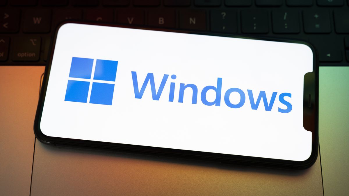 The Windows logo appears on the screen of a smartphone placed on a computer keyboard illuminated by orange and green light. Microsoft releases a major update to Windows 11 (25H2), and Windows 10 support ends permanently on October 14. In Creteil, France, on October 9, 2025. (Photo by Samuel Boivin/NurPhoto via Getty Images)