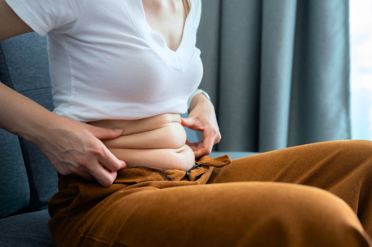 The woman grabs the flab on her stomach.