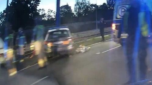 W nocy na drodze zatrzymany samochód, obok kilku funkcjonariuszy policji oraz karetka pogotowia.