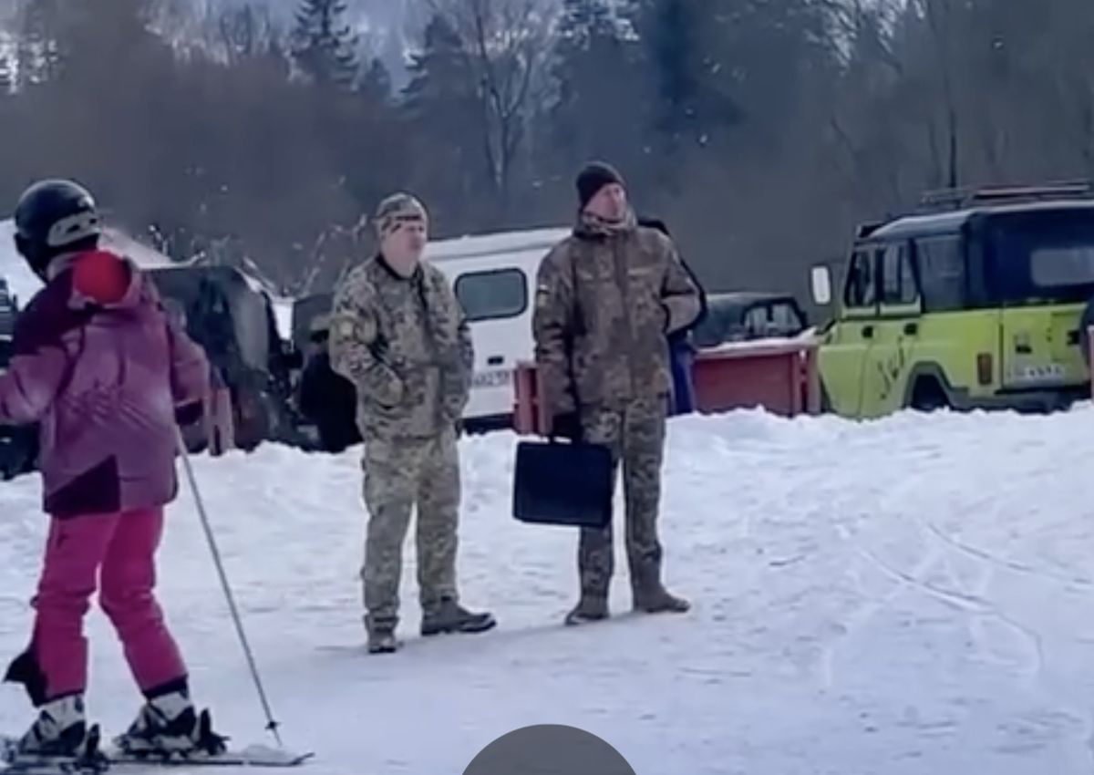Ukraińscy żandarmi z wezwaniem do stawienia się przed wojskową komisją uzupełnień cierpliwie czekają na pełnym narciarzy stoku w zimowym kurorcie