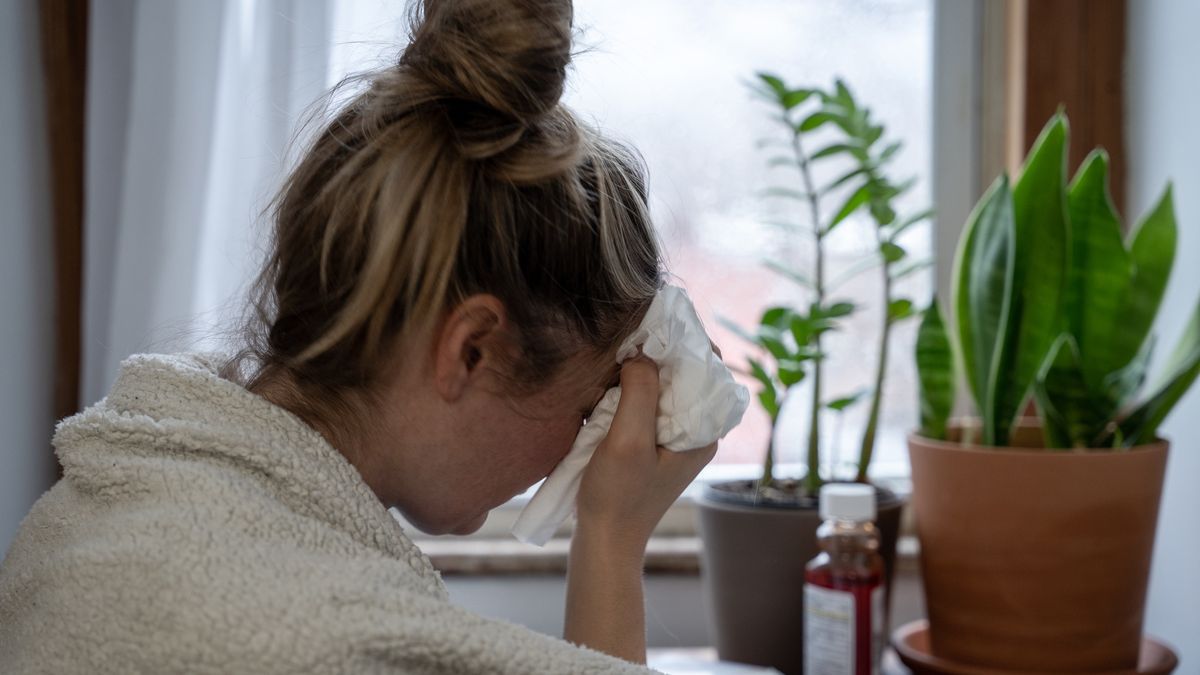 A young woman sick at home stares out the window on a rainy day.Sickness is a part of every day life and resting at home is an important part of getting back to good health.MundusImages