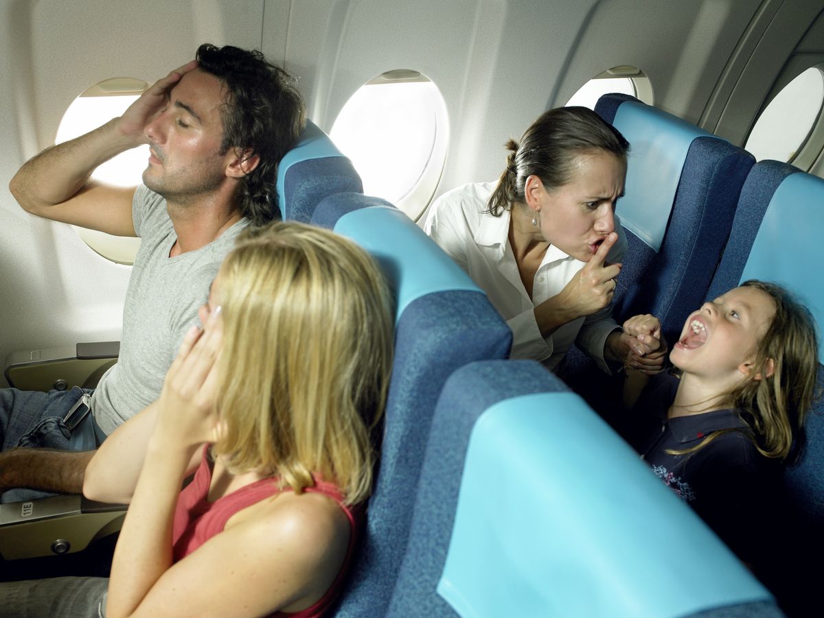 Girl yelling behind young couple in airplane

