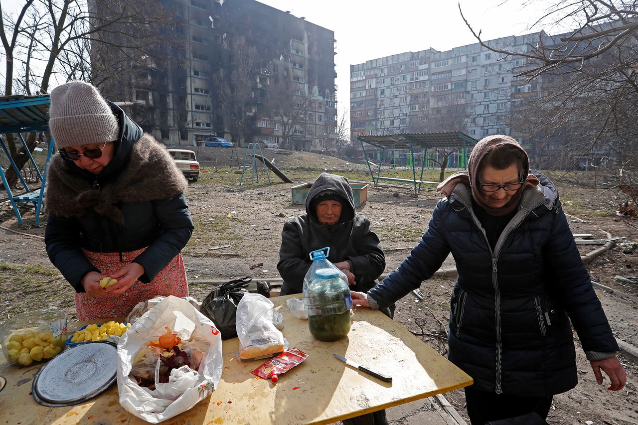 Mieszkańcy przygotowują jedzenie na zniszczonym osiedlu w Mariupolu.