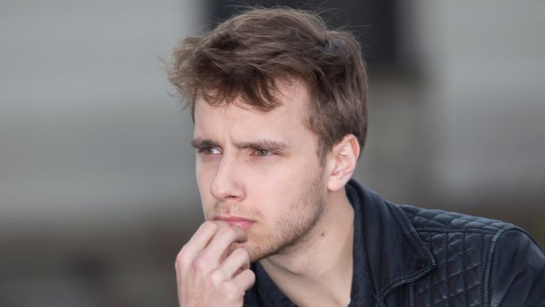 Maciej Musiał eksponuje muskulaturę, pozując na tle ferrari