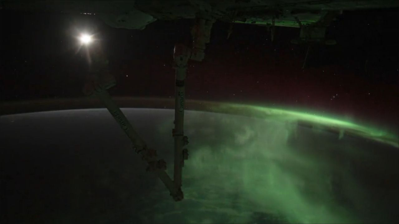 Ksieżyc widoczny z pokładnu ISS z zorzą polarną w tle.