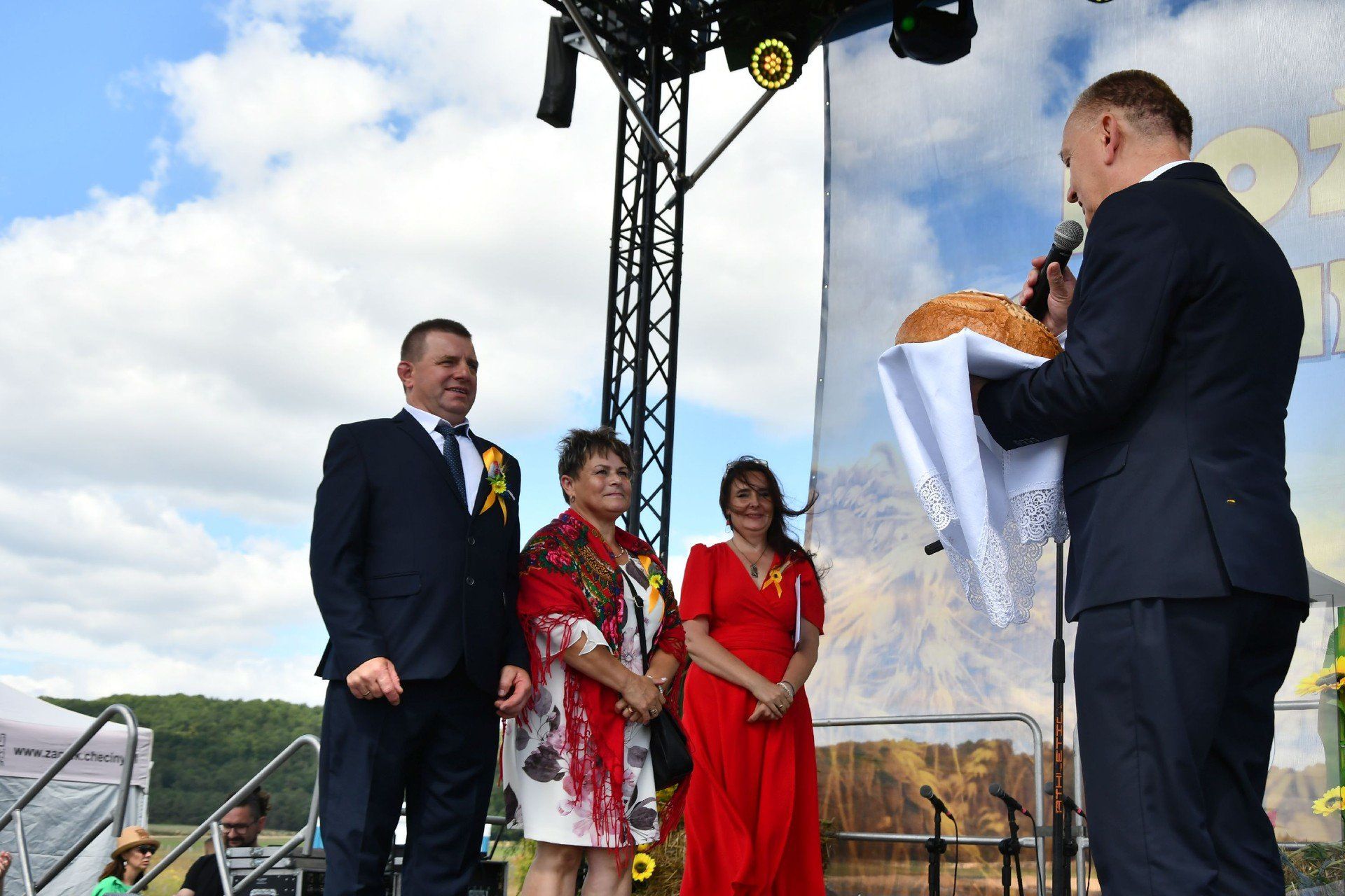 Dożynki 2025 gminy Chęciny w Mostach. Przekazanie chleba burmistrzowi Robertowi Jaworskiemu przez starostów dożynek. 