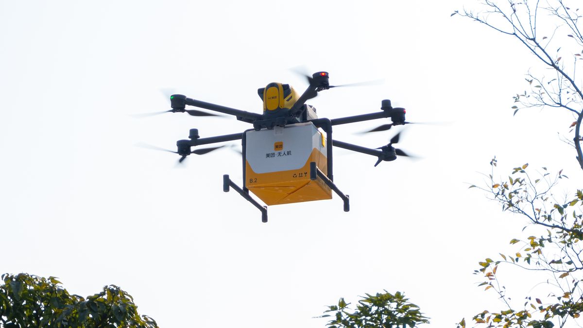 SHENZHEN TALENT PARK, SHENZHEN, CHINA – 2024/12/29: A Meituan drone delivers food to citizens at the Shenzhen Talent Park in Shenzhen. Meituan has launched a drone delivery service for food, including a new route to the Great Wall of China in Beijing, marking the city's first commercial drone delivery. The company also operates over 30 drone delivery routes in cities like Shenzhen, Shanghai, and Guangzhou. Drones follow fixed routes from depots to landing sites, with delivery workers managing package transfers between merchants, depots, and customers. This service provides a faster and more efficient way to deliver food and supplies, especially to hard-to-reach areas. It highlights Meituan's innovative approach to addressing logistical challenges in modern delivery systems. (Photo by Peerapon Boonyakiat/SOPA Images/LightRocket via Getty Images)