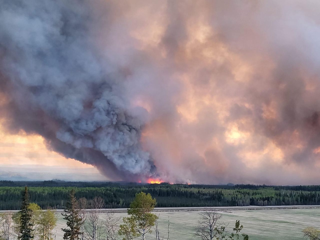 FORT NELSON, BRITISH COLUMBIA, CANADA - MAY 14: Smoke rises after fire erupts in Western Canada on May 14, 2024. Wildfires in Western Canada prompted thousands to flee their homes, while 66,000 were on standby to evacuate as a fast-moving blaze threatened another community Saturday. A growing wildfire moved relentlessly toward Fort Nelson, British Columbia (B.C.), resulting in officials ordering more than 3,000 to leave their homes in Fort Nelson and nearby Fort Nelson First Nation.Within five hours, the fire had grown to 8 square kilometers. (3 square miles) from a modest half square kilometer.Tinder dry conditions and flames fanned by powerful winds caused the wildfire to spread and prompted the evacuation order, which was issued at 7.30 p.m. (Photo by Cheyenne Berreault/Anadolu via Getty Images)