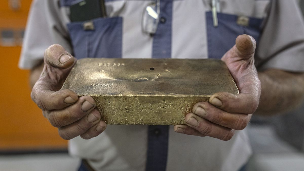 A worker displays a gold bar at the Elikhulu Tailings Retreatment Plant, which extracts traces of gold from old mine waste, in Evander, South Africa, on Friday, Aug. 4, 2023. In May 2022, fed up with the Eskom-imposed electricity rationing that forced the company to curtail its power use by as much as 20%, gold mining company Pan African decided to hire JUWI South Africa to build a 10-megawatt solar farm to power its treatment plant east of Johannesburg. Photographer: Guillem Sartorio/Bloomberg via Getty Images