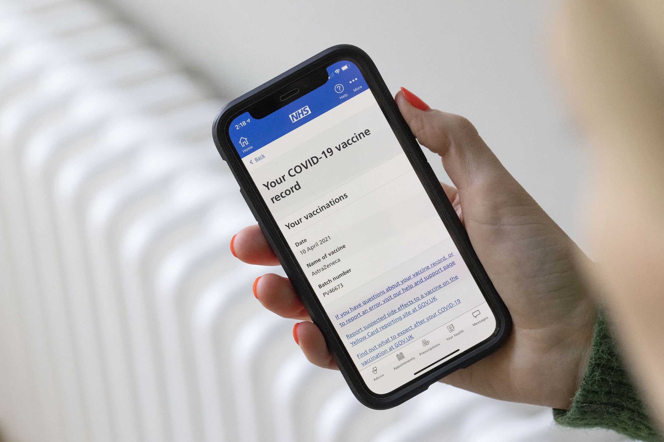 A woman uses the National Health Service (NHS) app, showing a Covid-19 vaccine record, on a smartphone arranged near Guildford, U.K., on Monday, May 17, 2021. As the bans on international travel and households mixing indoors are relaxed, the National Health Service mobile app has started showing individuals vaccine status, a key step in the development of so-called Covid passports that will be key to enabling foreign trips. Photographer: Jason Alden/Bloomberg via Getty Images