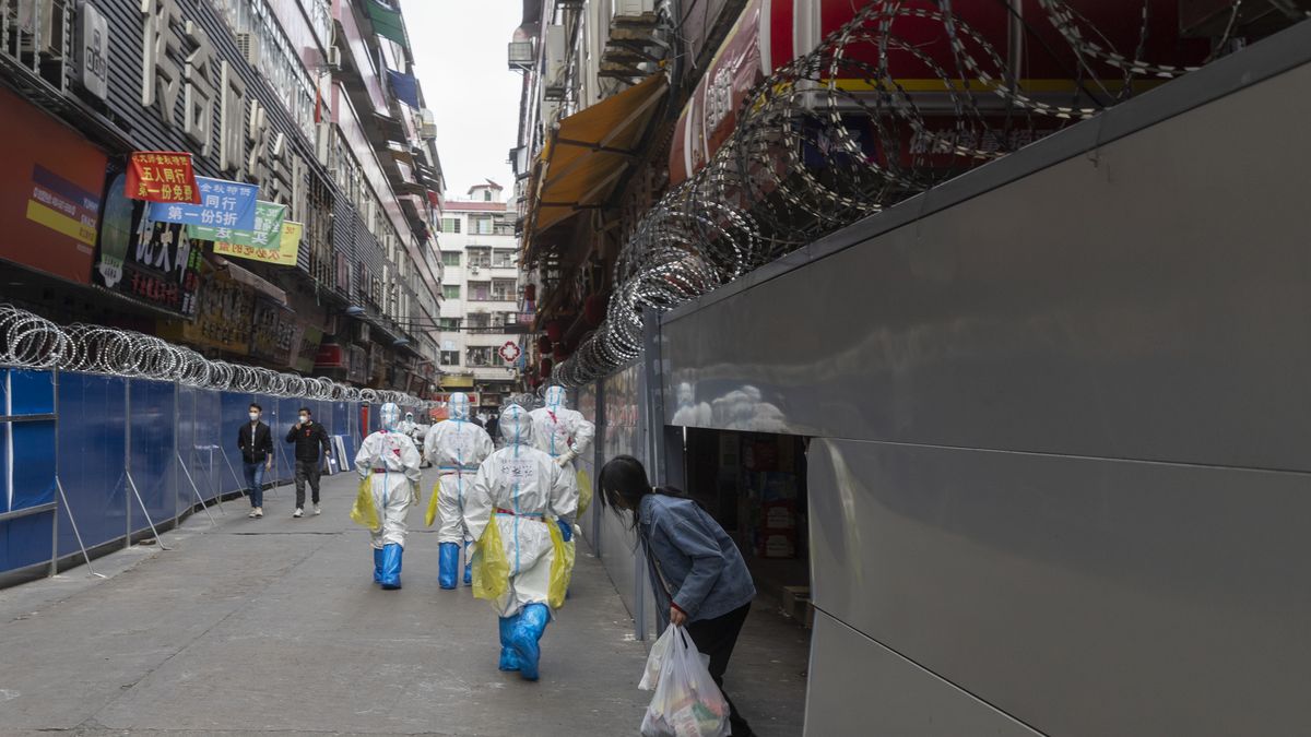 GUANGZHOU, CHINA - DECEMBER 06 2022: A group of government workers in PPE walk by walls enclosing buildings under the Covid-19 lockdown in Guangzhou in south China's Guangdong province Tuesday, Dec. 06, 2022. (Photo credit should read JULIEN TAN / Feature China/Future Publishing via Getty Images)