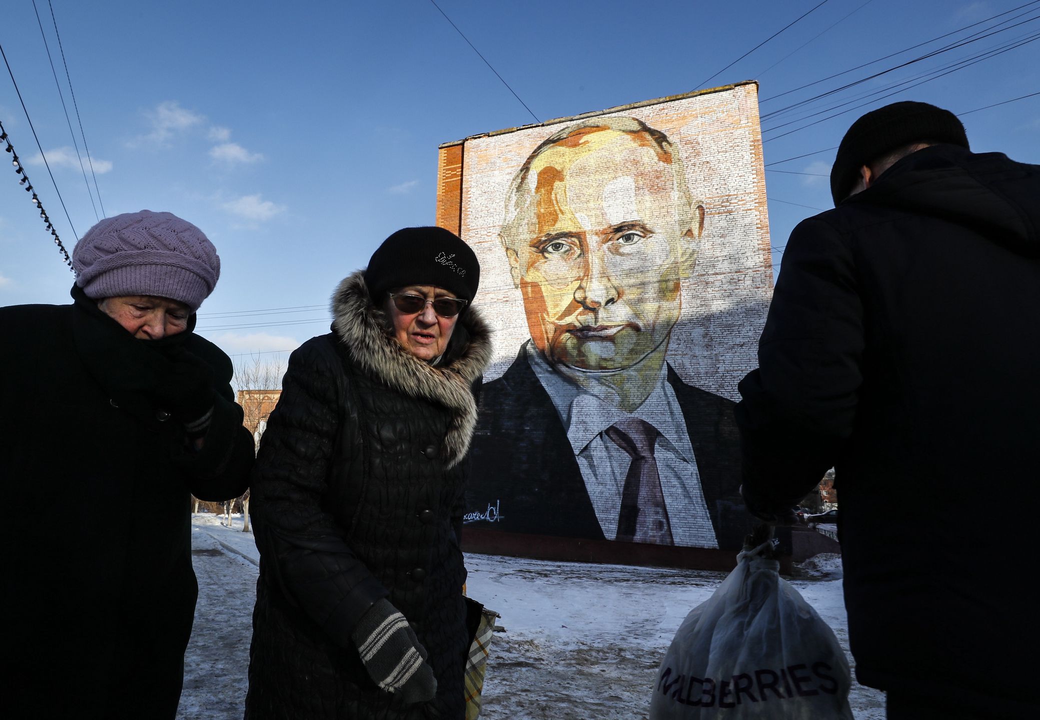 People walk past a large mural depicting Russian President Vladimir Putin, on the side of a five-story residential building in Kashira, Moscow region, Russia, 12 January 2023. The years-old mural was created by activists of the pro-Kremlin movement Molodaya Gvardiya (Young Guard). EPA/YURI KOCHETKOV Dostawca: PAP/EPA.